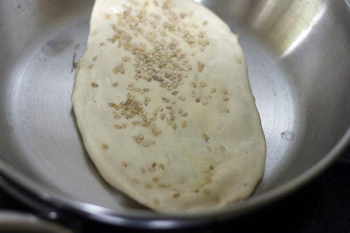 cooking rolled kulcha in a flat pan