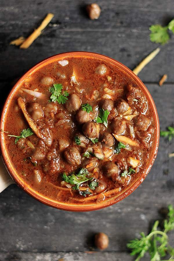 Traditional amritsari chole garnished with ginger juliennes served in a ceramic bowl. 