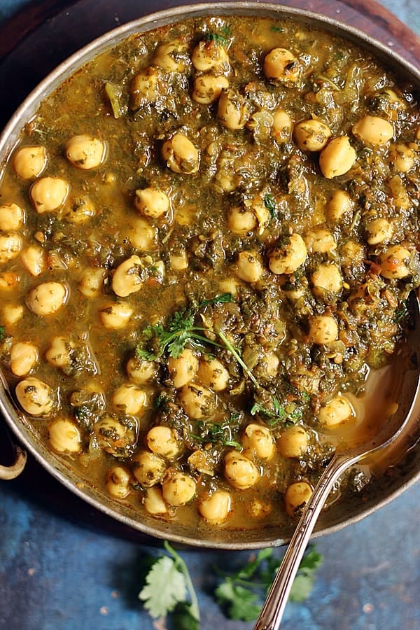 easy vegan chana saag served in a copper kadai with a spoon.