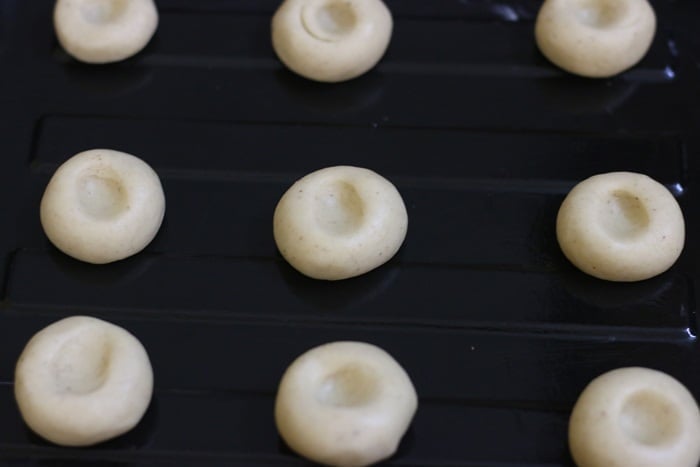shaped thumbprint cookies arranged on a cookie sheet.
