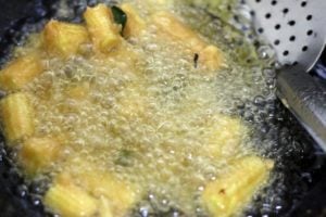 frying batter coated baby corn in hot oil