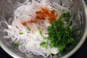 chopped coriander leaves and red chili powder added to sliced onions.