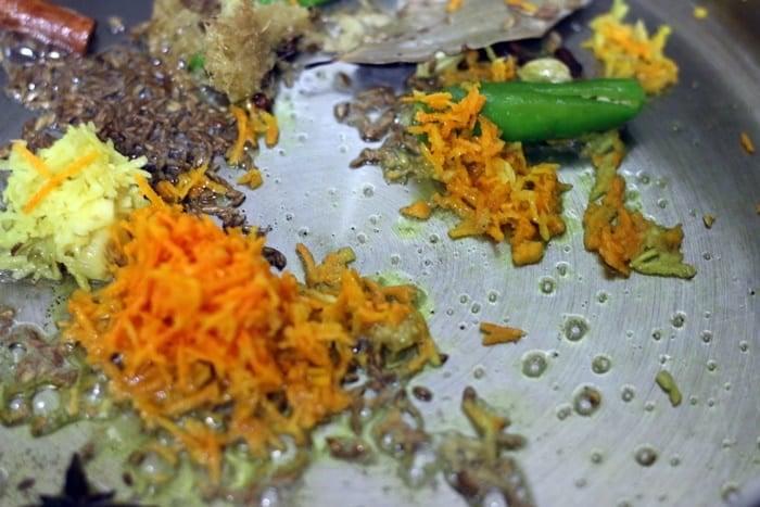 sauteing cumin seeds, grated turmeric, ginger, green chili in oil for making turmeric rice recipe.