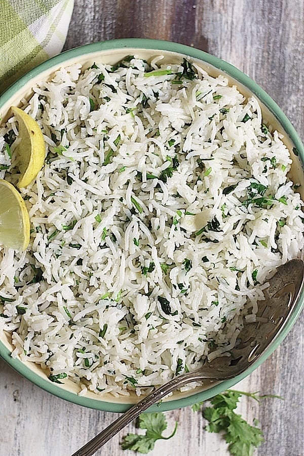 cilantro lime rice served in a green rimmed bowl with a spoon