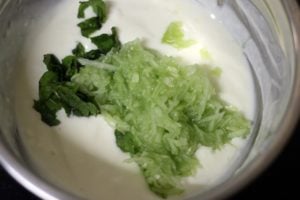 grated cucumber and mint leaves added to whisked curd