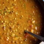 closeup shot of homemade green moong dal curry in a copper pan.