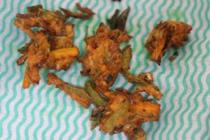 draining excess oil from fried pakoras