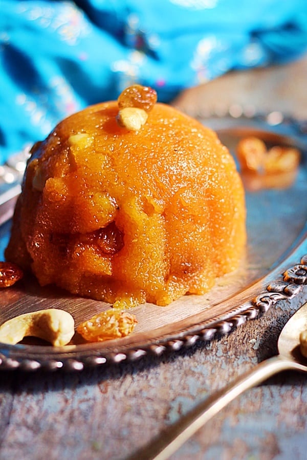 Homemade rava kesari served in a silver plate garnished with cashews and raisins