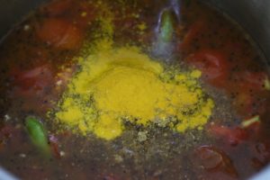 turmeric powder added to boiling tomato rasam