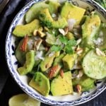 close up of cucumber avocado salad in a blue ceramic bowl