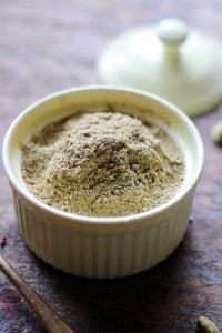 Homemade green cardamom powder in a ceramic jar