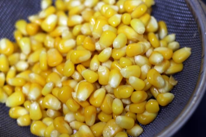 boiled corn kernels in a colander
